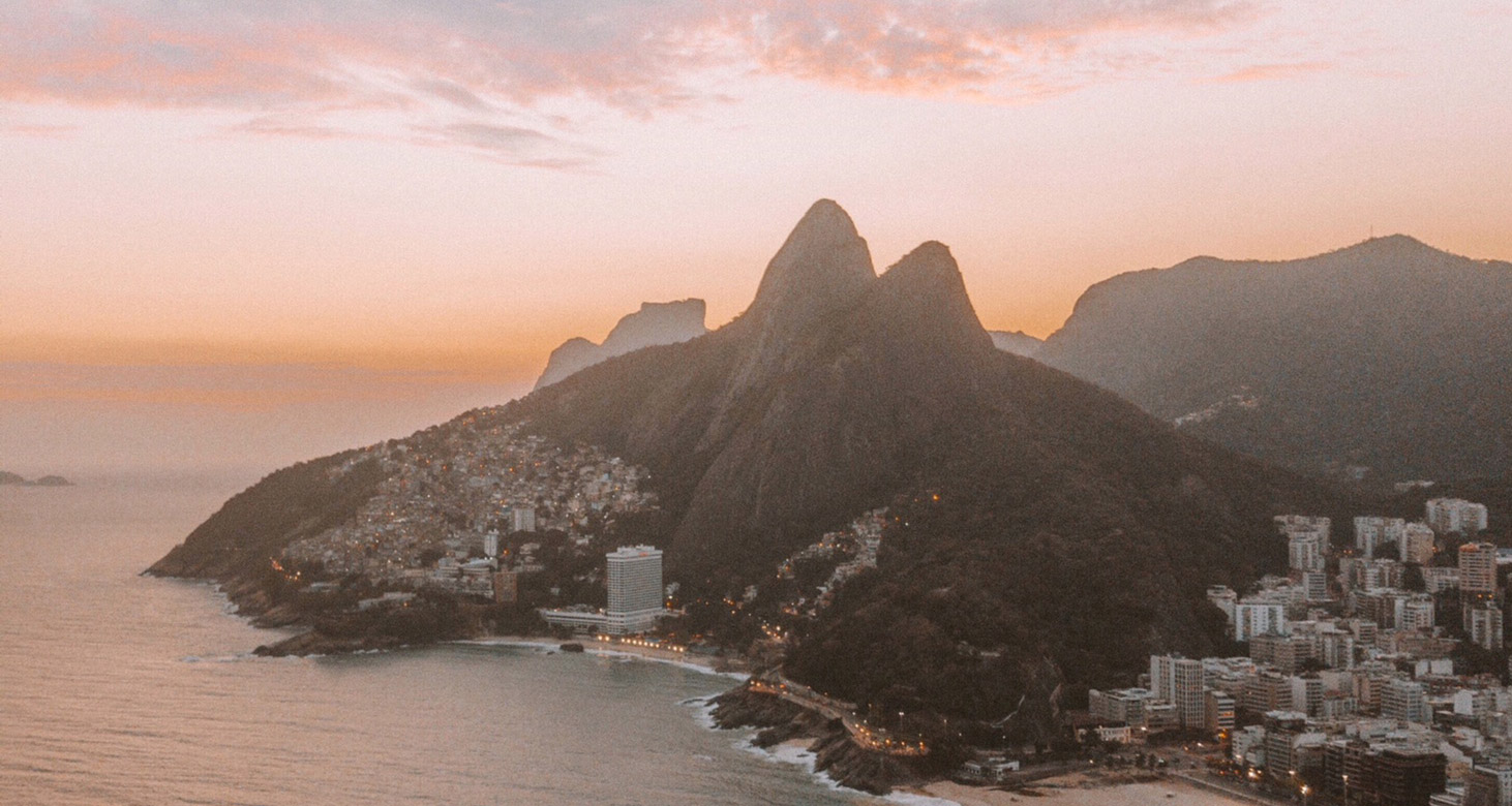 Imagem aérea do morro dos Dois Irmãos com o por do sol laranja ao fundo