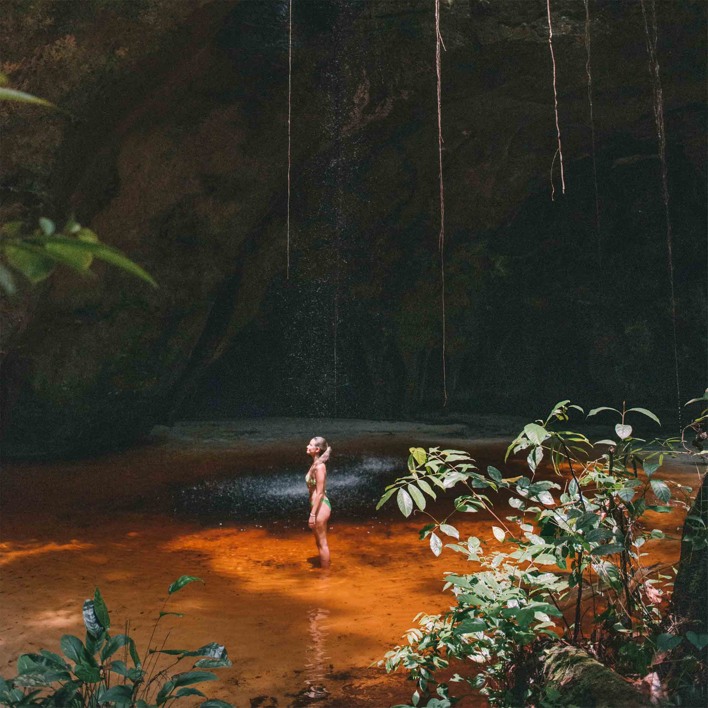 Mulher no meio da Caverna Refúgio do Maroaga com os pés na água 