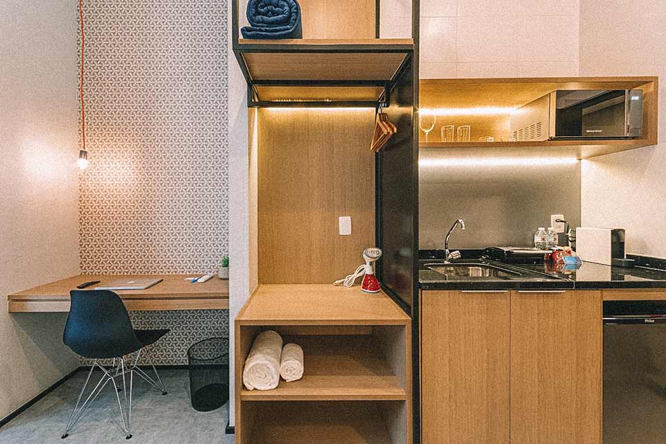 Minicopa, armário e espaço de escritório lado a lado em apê em SP.