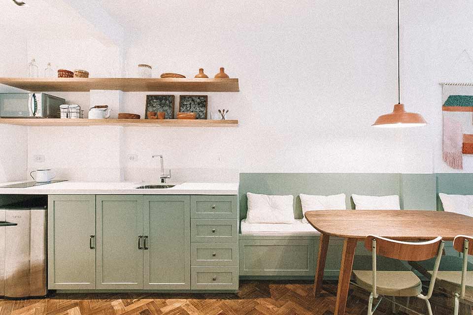 Cozinha com armários verdes, integrada à sala de estar.