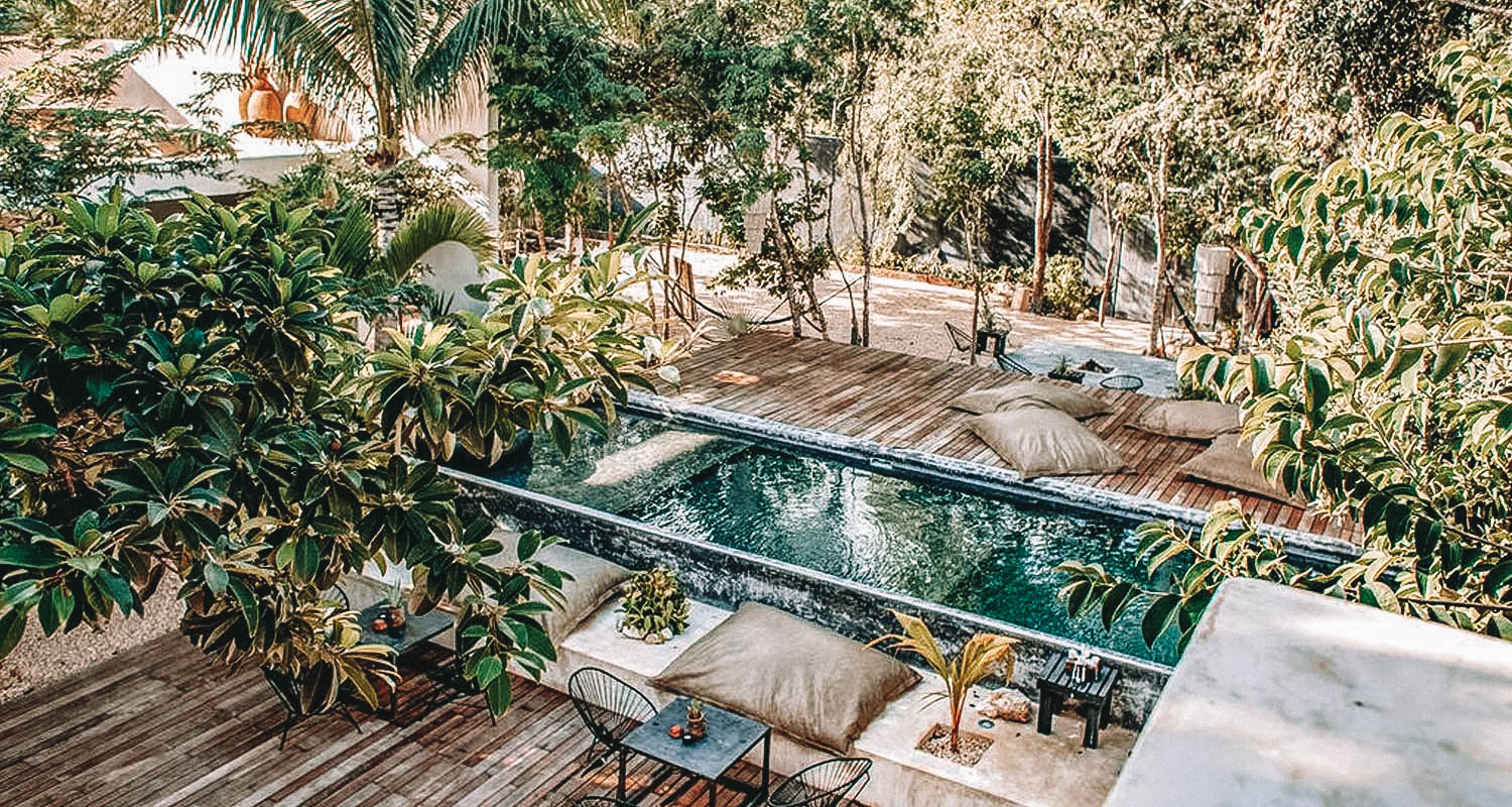 Vista da avranda da piscina com vegetação ao redor e deck de amadeira com espreguiçadeiras