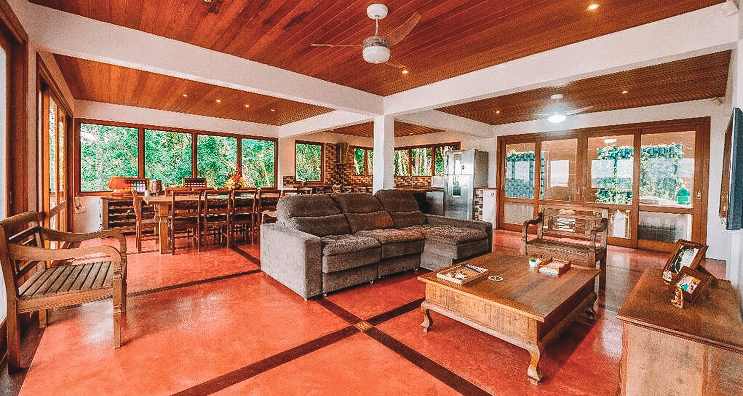 Ampla sala de estar com janelões, teto em madeira e decoração rústica