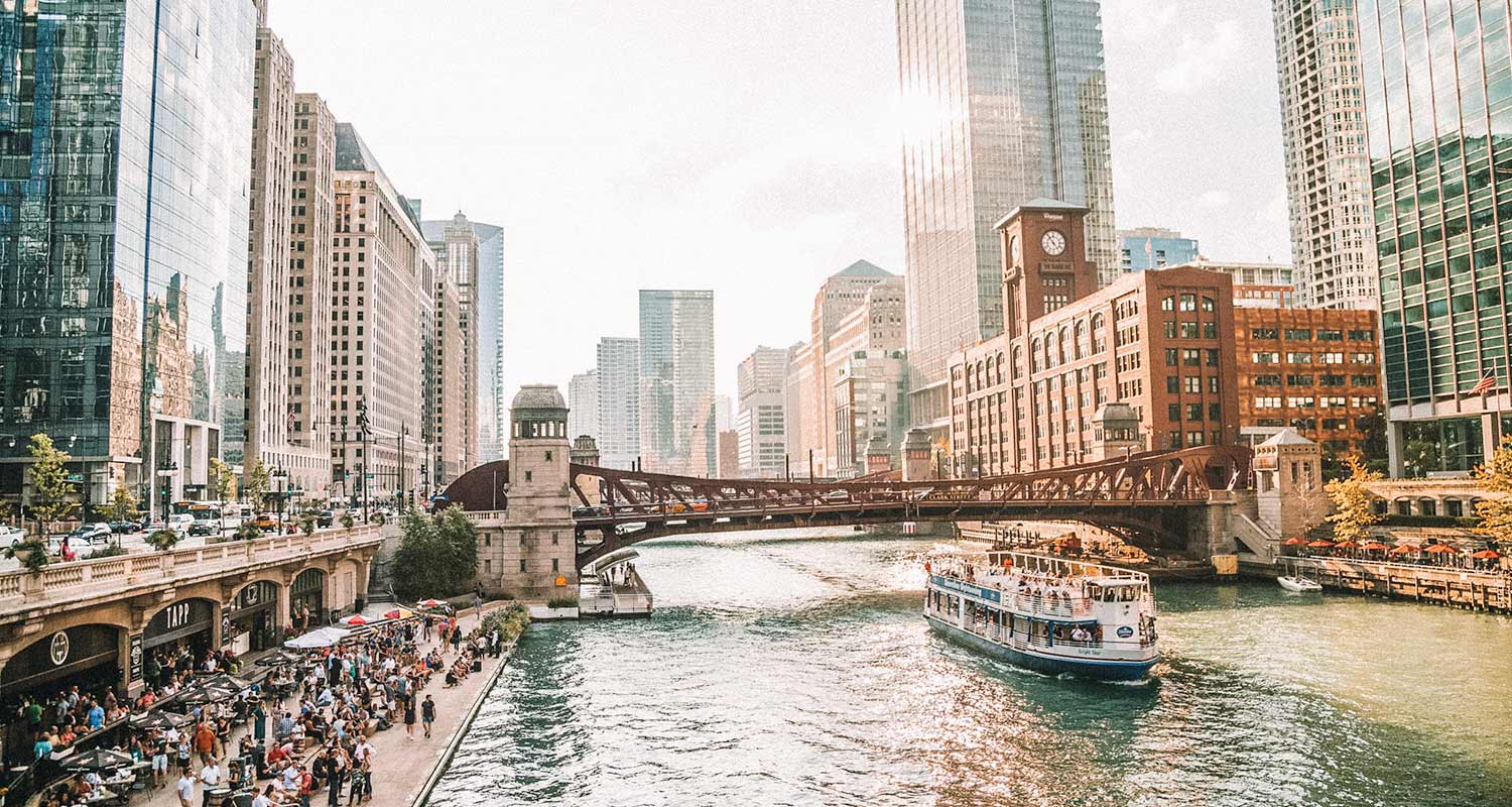 Barco no Lago Michigan em Chicago, com prédios ao redor e pessoas no calçadão