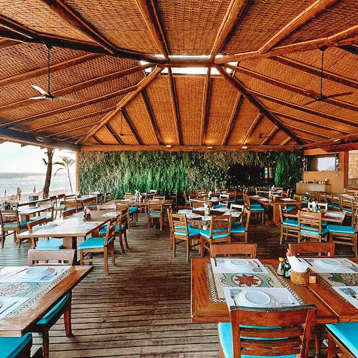 Restaurante praiano Badauê, com mesas e cadeiras de madeira 