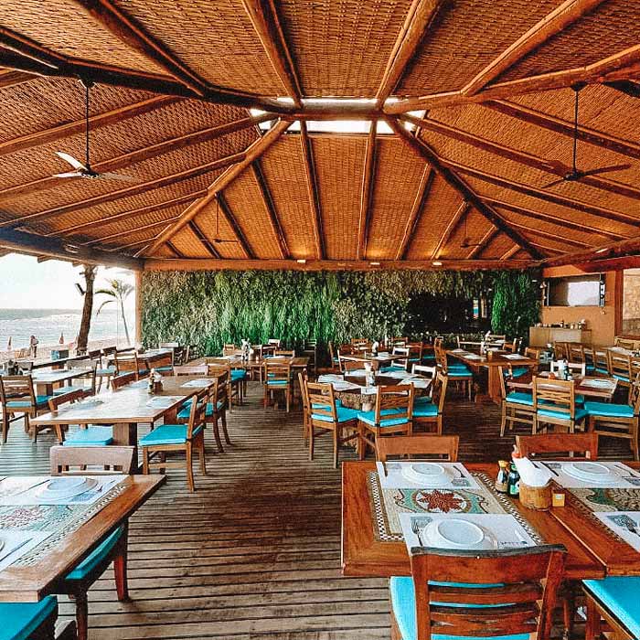 Restaurante praiano Badauê, com mesas e cadeiras de madeira