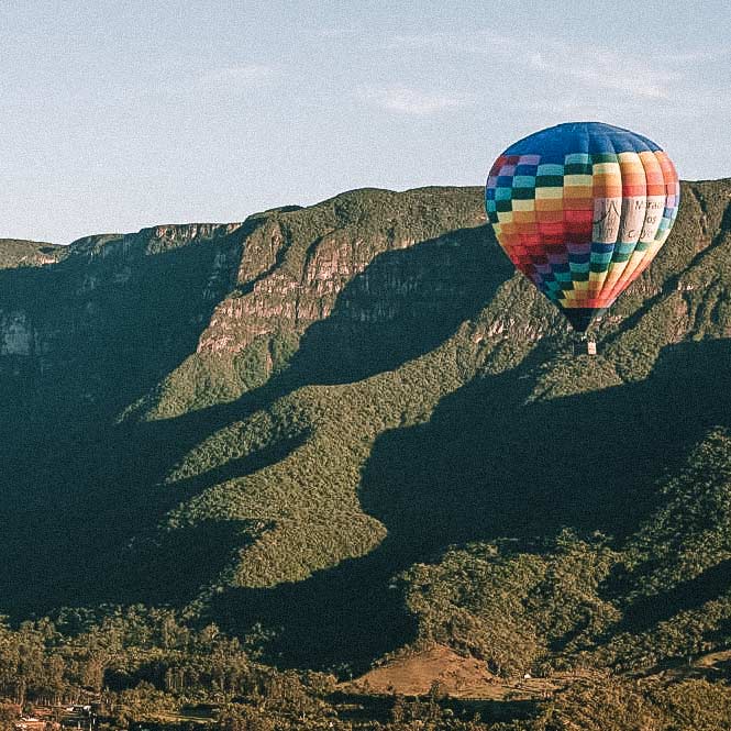 Balão colorido voando em frente ao cânion, em Praia Grande, Santa Catarina. Passeios de balão no Brasil.