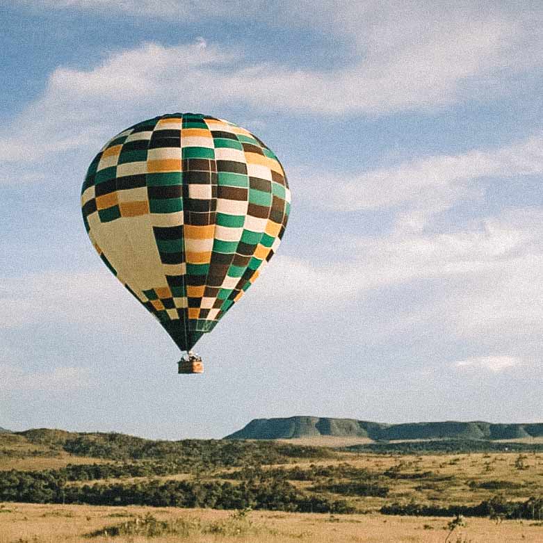 Balão marrom, amarelo, verde e branco no horizonte da Chapada dos Veadeiros. Passeios de balão no Brasil.