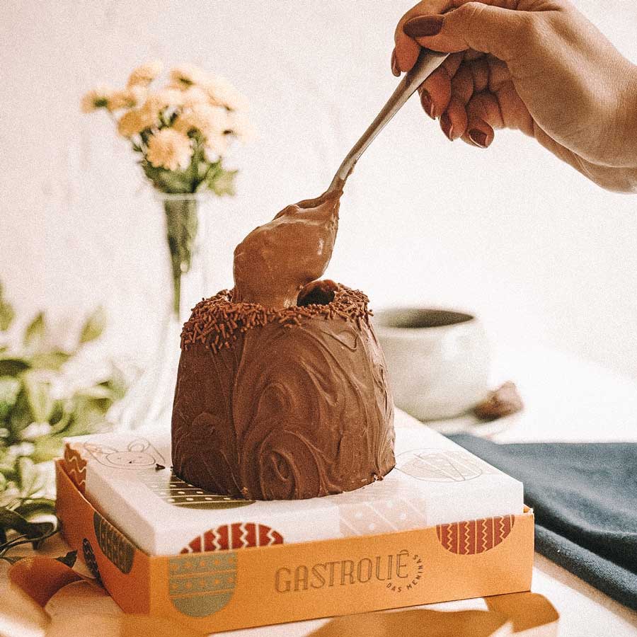 Ovo de Páscoa recheado com mulher retirando uma colher de recheio de chocolate ao leite, na Gastroliê das Meninas