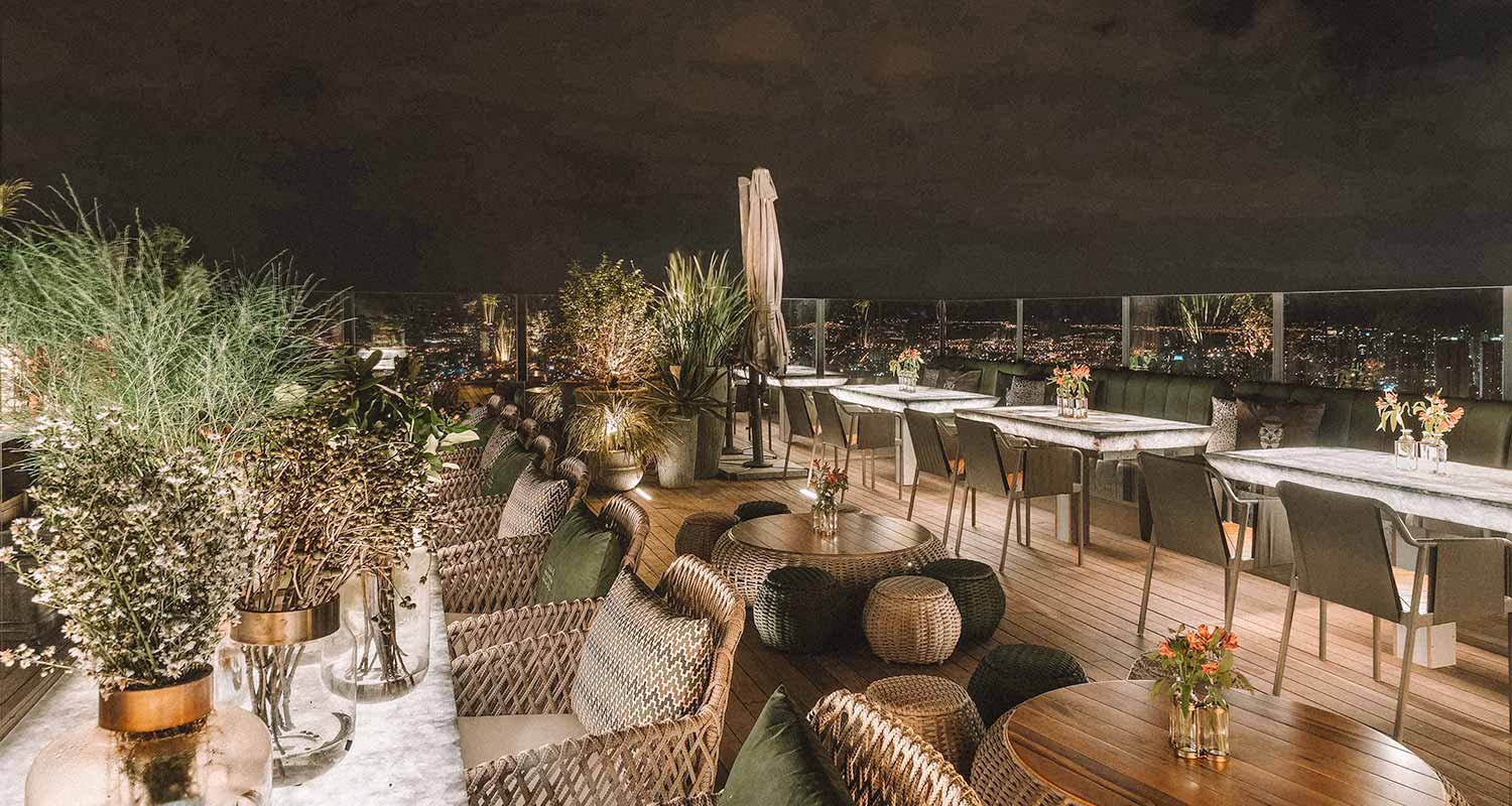 Mesas e cadeiras no topo do Grá Rooftop, à noite, em Goiânia, Goiás