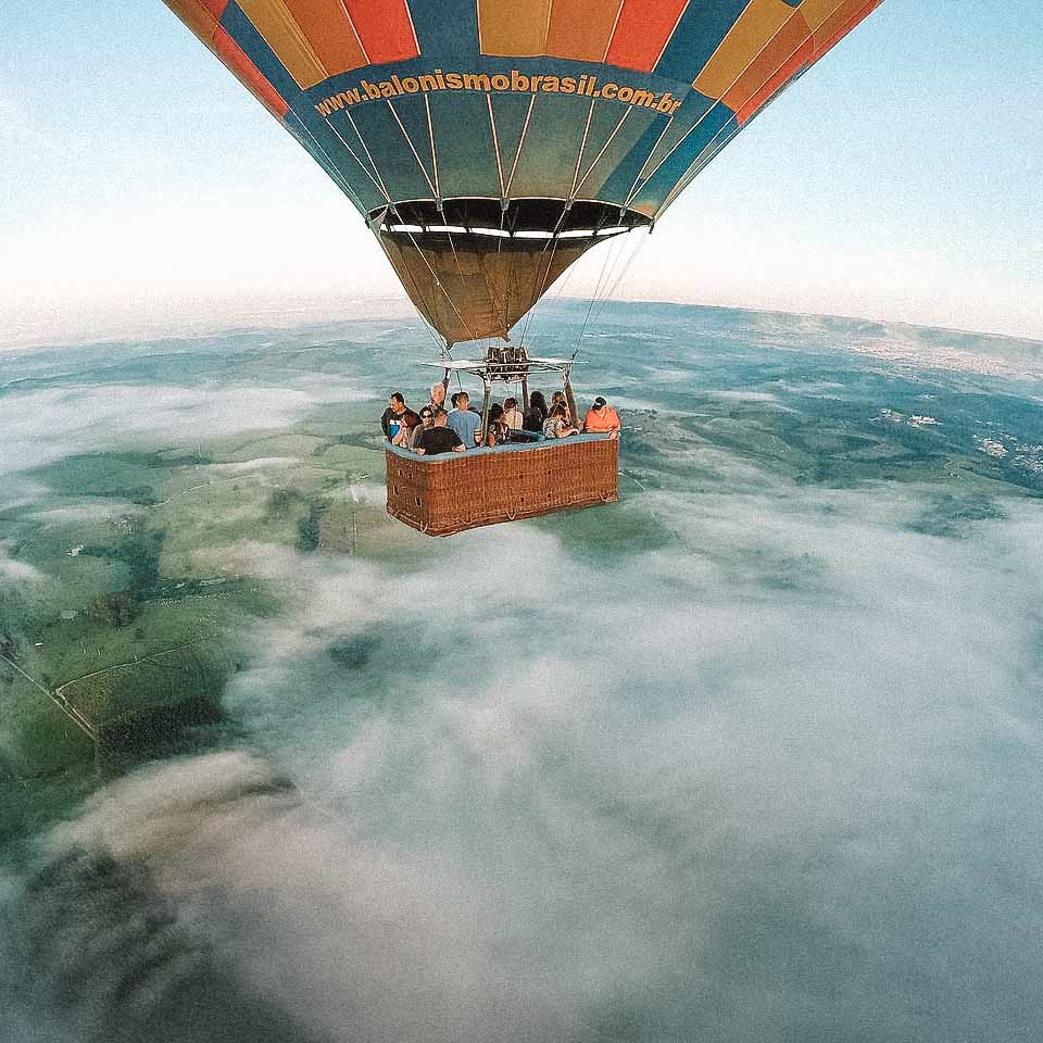 Pessoas no balão sobrevoando um espaço com névoa, em São Pedro