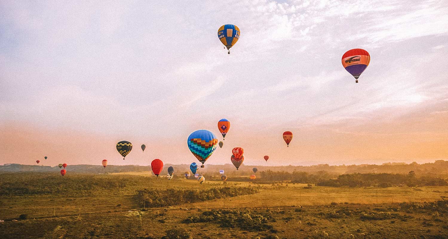 Vários balões voando no horizonte ao pôr do sol, em Torres, no Rio Grande do Sul