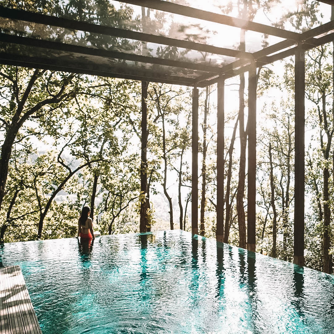 Mulher dentro da piscina com vista para a mata