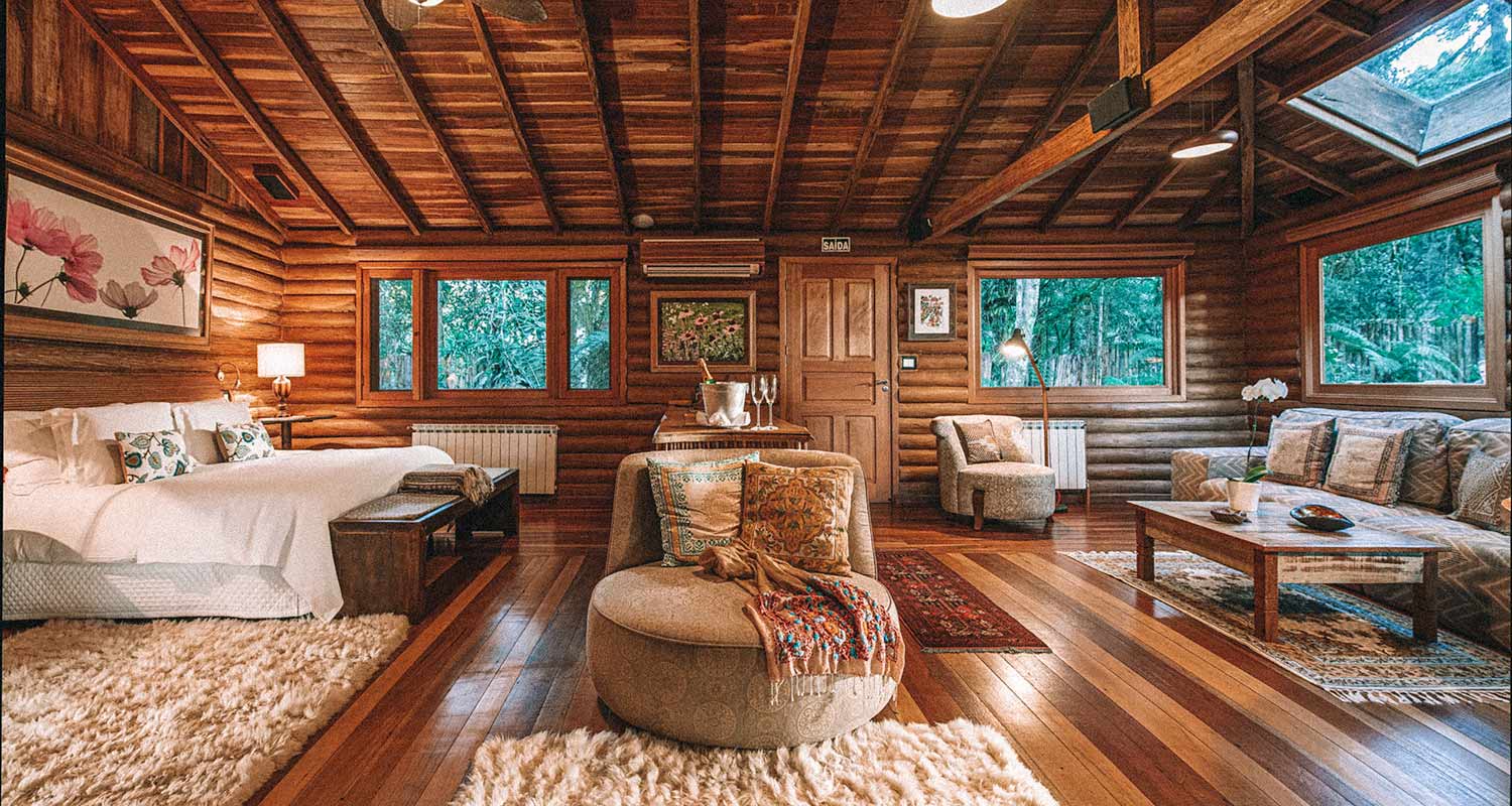 Quarto todo em madeira e bem amplo, com poltronas, sofás e cama de casal. Uma das pousadas e hotéis no Rio Grande do Sul