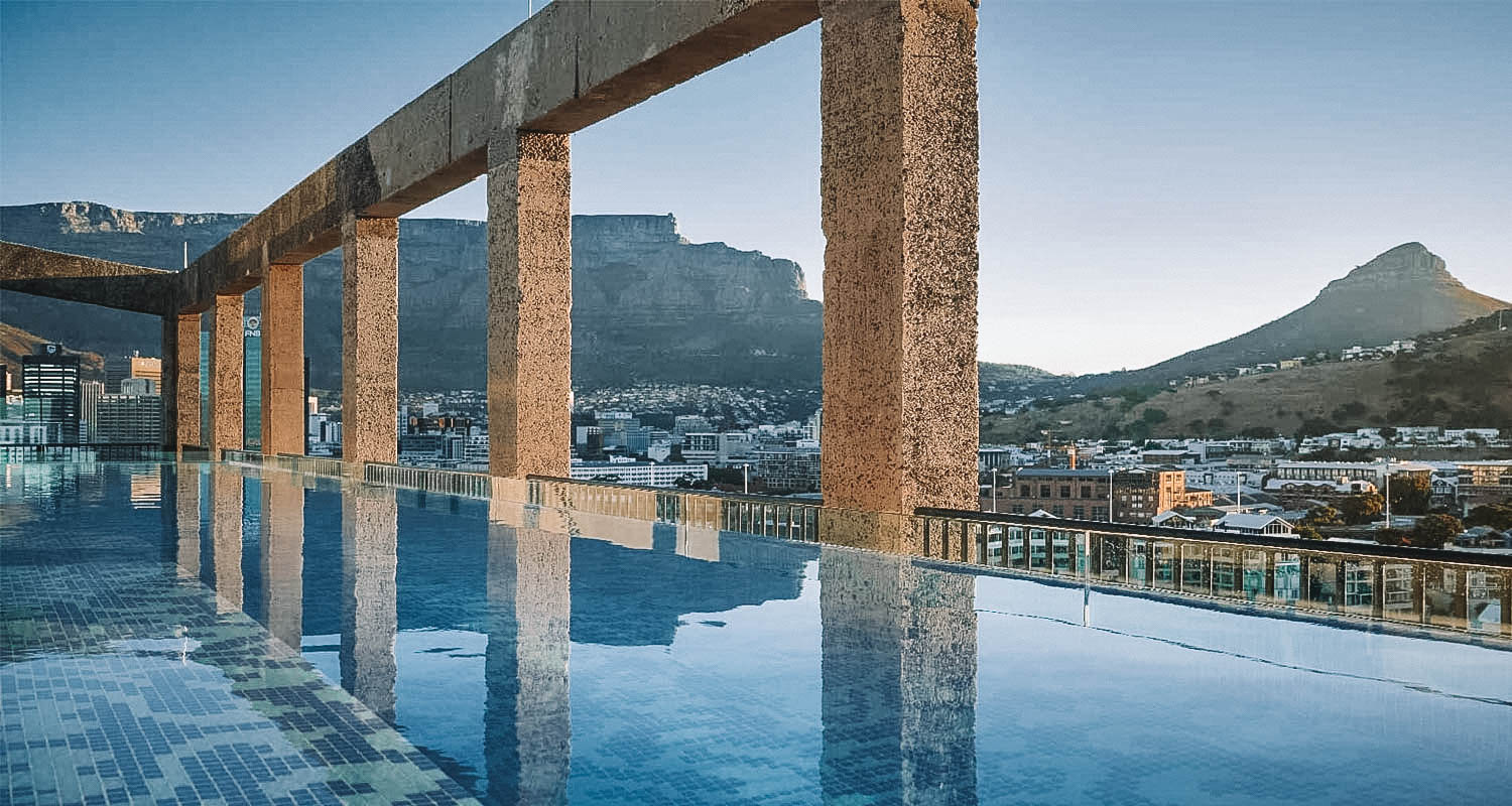 Piscina com borda infinita e paredões de vidro com paisagem das Table Mountains