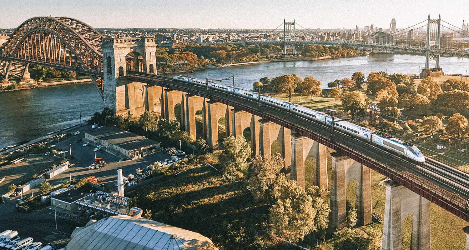 Trem passando em ferrovia suspensa com cidade ao fundo