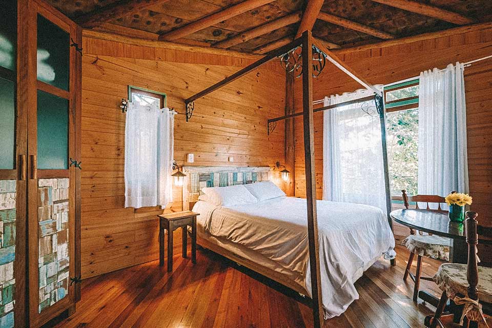 Cama de casal em quarto rústico com elementos de madeira