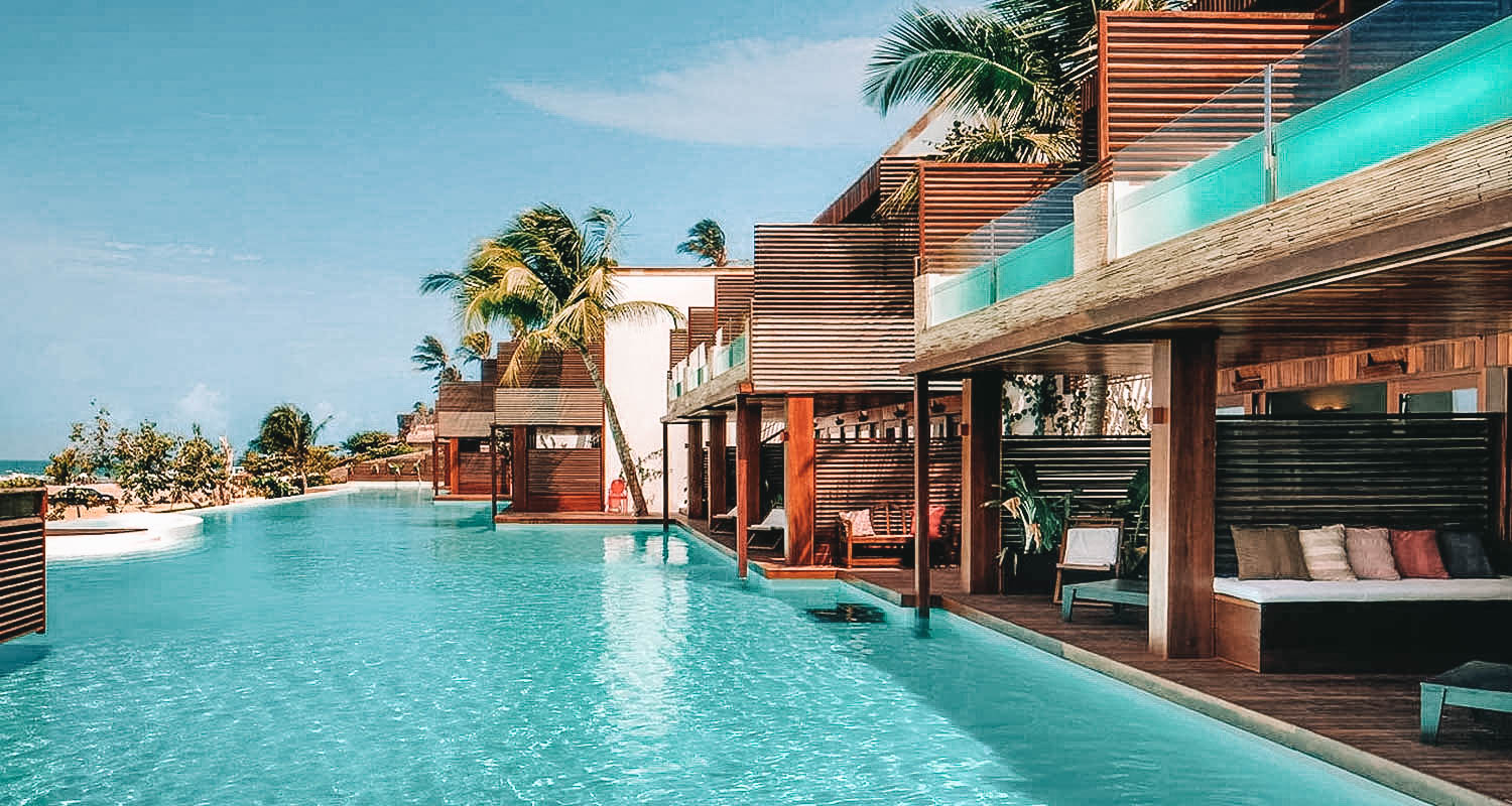 Piscina com borda infinita com quartos ao lado, sendo que os superiores tem suas próprias piscinas particulares