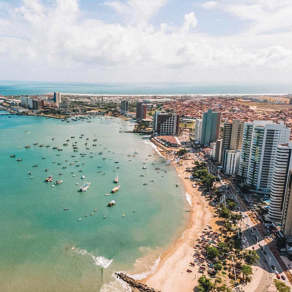 Praia com barcos no mar e prédios em frente à praia, em Fortaleza, uma das maiores cidades da América do Sul