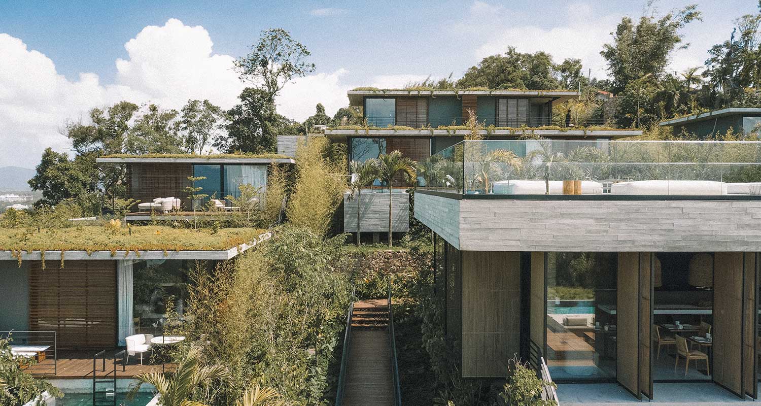 Fachada do hotel Fuso, com estrutura de vidro, madeira e muitas plantas ao redor