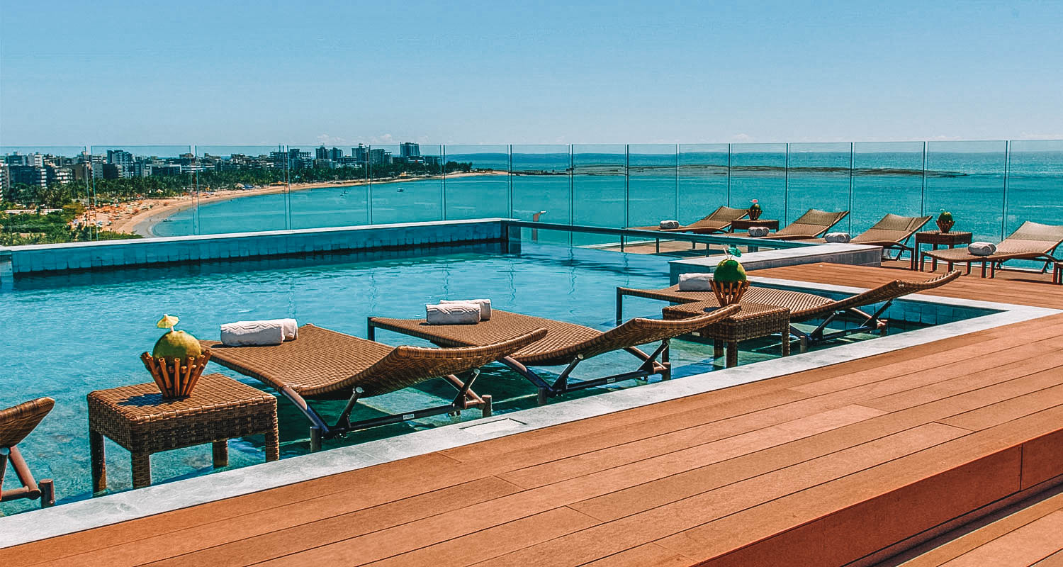 Piscina ao ar livre com deck em madeira e vista para o mar de maceió