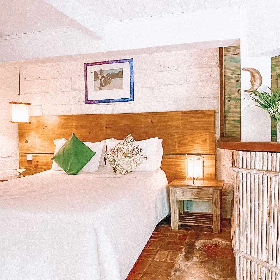 Quarto praiano, com cama com lençóis brancos e almofadas em cima