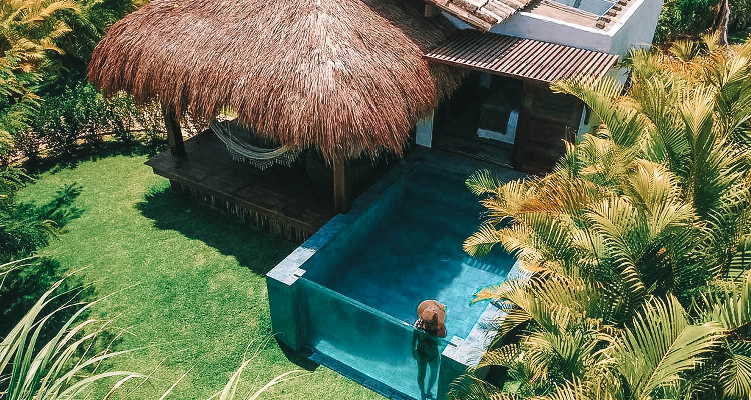 Bangalô com teto de piaçava e piscina no estilo aquário