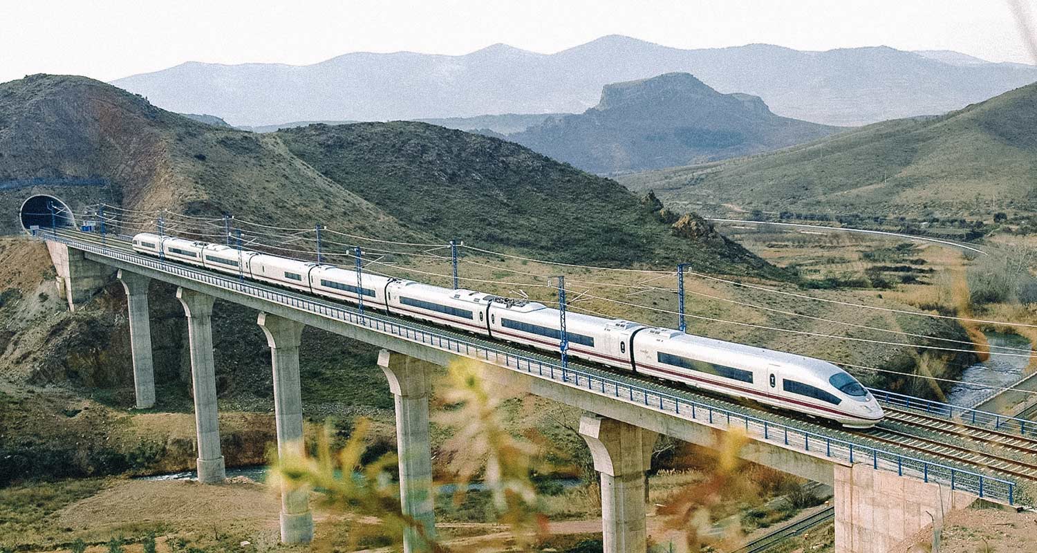 Trem passando por rodovia suspensa em ambiente serrano