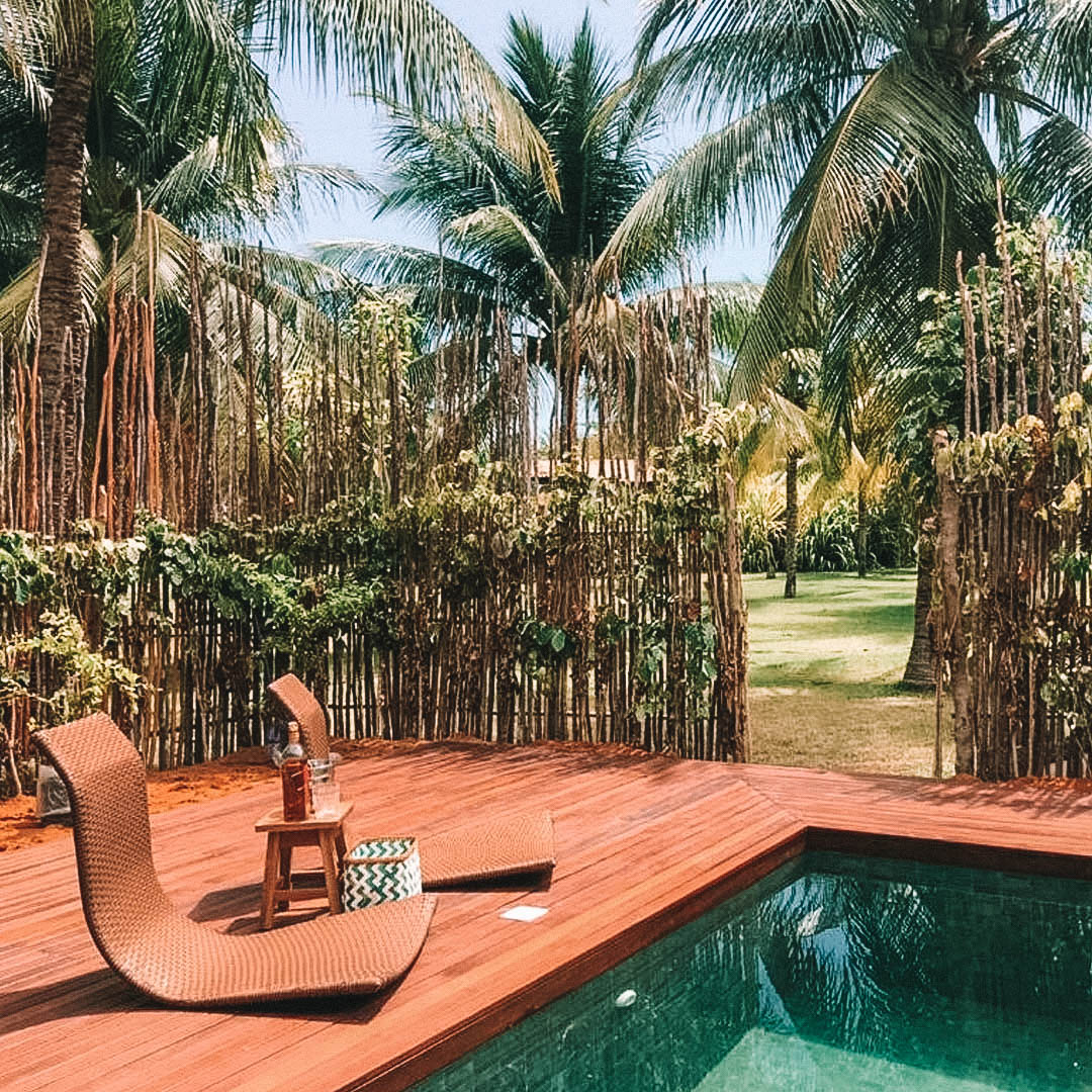 Deck de madeira envolto na piscina e uma cadeira com apoio