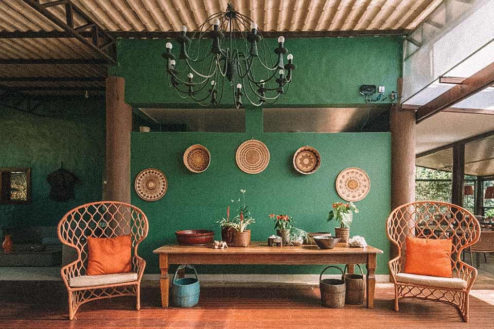 Lounge com poltronas de bambu, ornamentos rústicos e parede verde