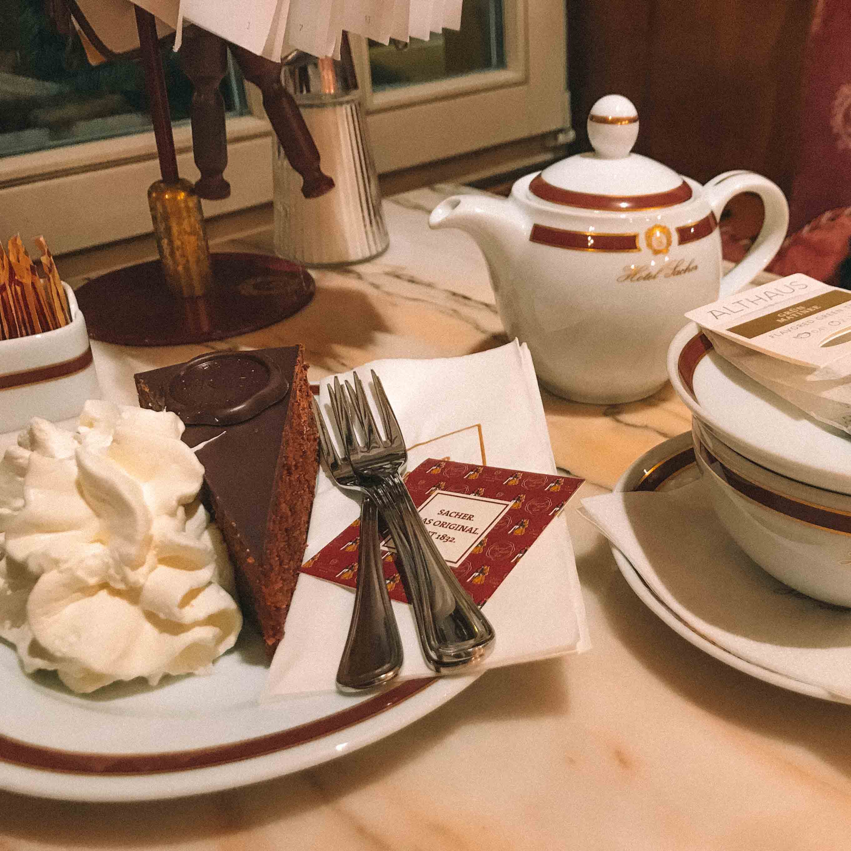 Imagem da famosa Torta Sacher com uma xícara e um bule de chá ao lado