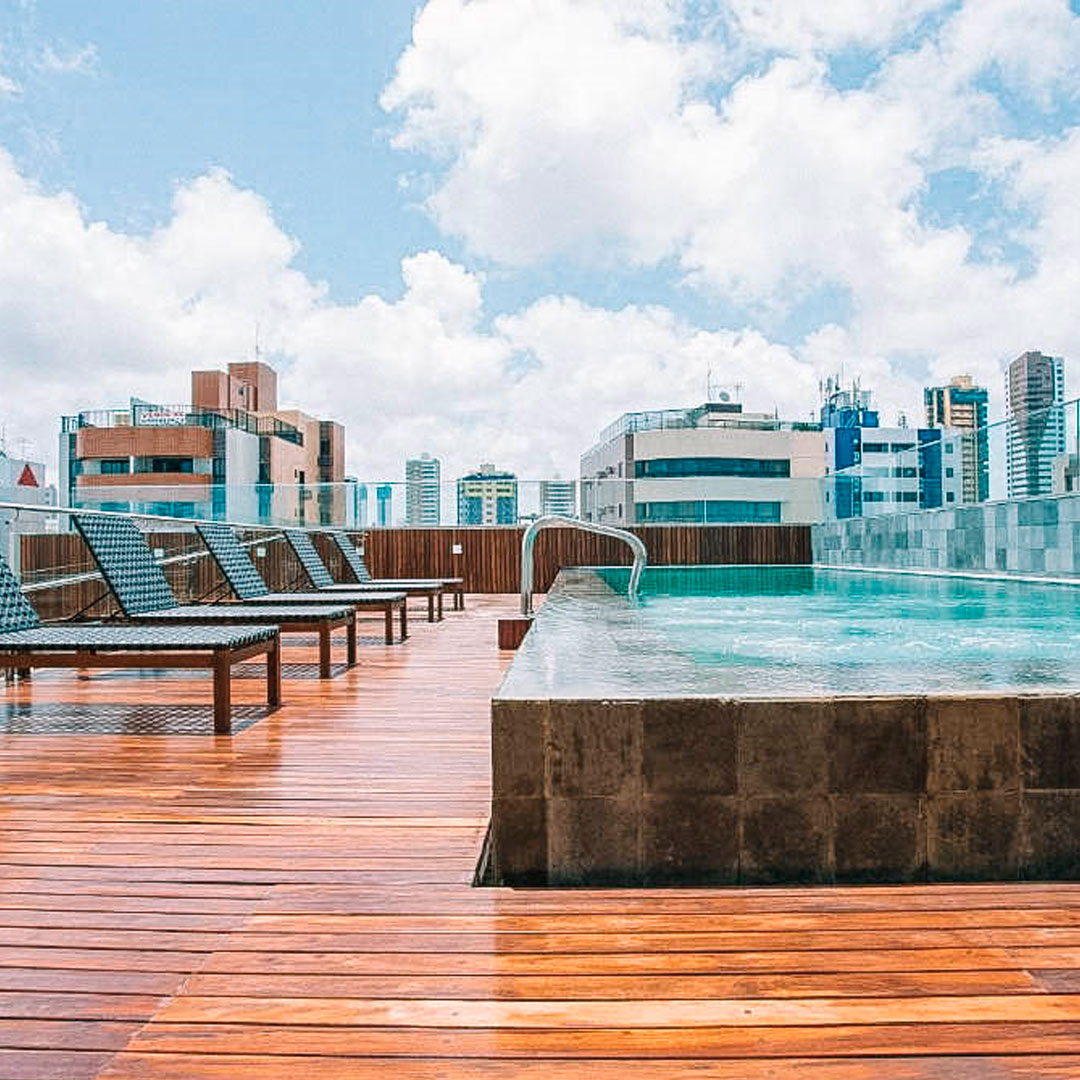 Deck de madeira com a piscina ao lado e vista da cidade