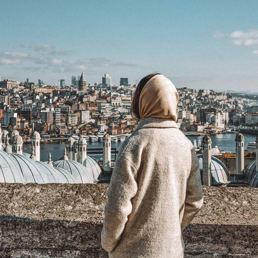 Mulher com lenço na cabeça olhando a cidade do alto