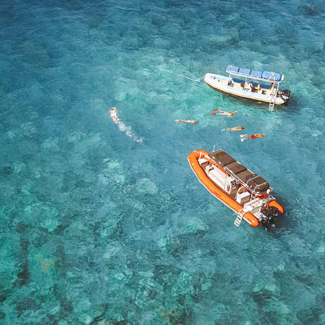Dois barcos e pessoas nadando em águas cristalinas no Havaí, EUA