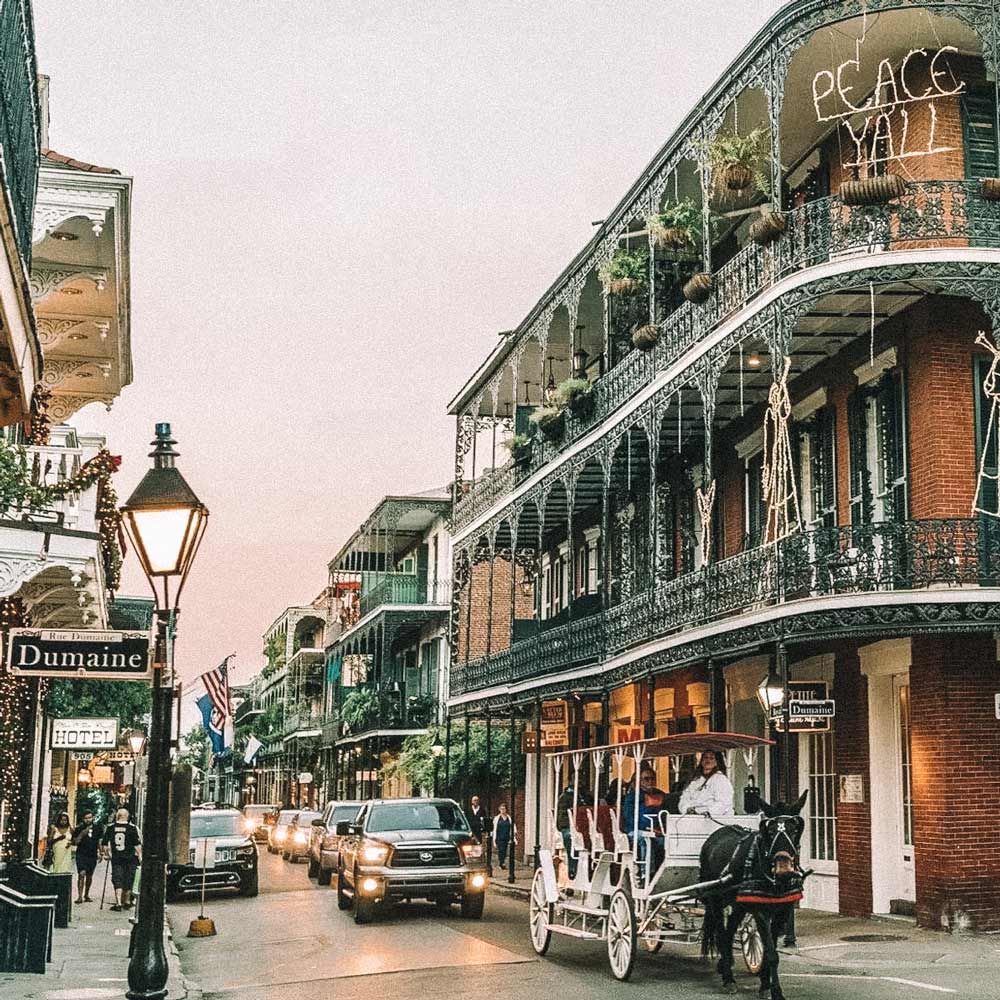 Avenida em Nova Orleans, EUA, com carros e uma charrete passando