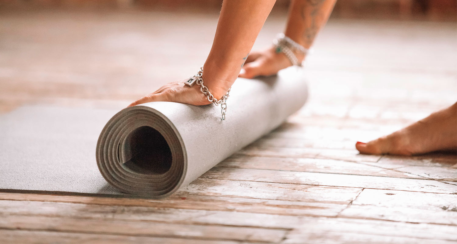 mulher enrolando um tapete de yoga