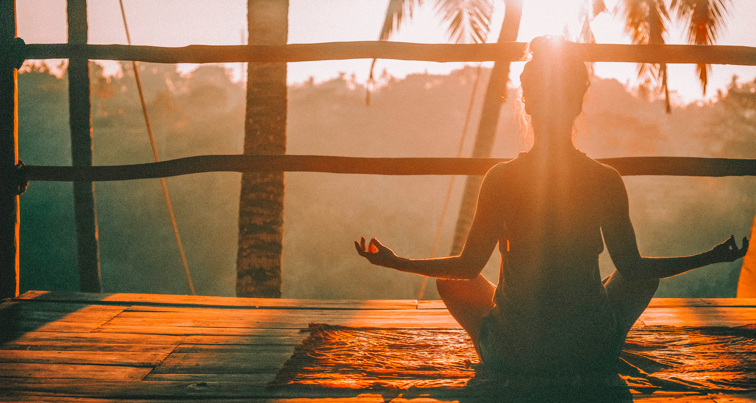 Mulher fazendo yoga no nascer do sol